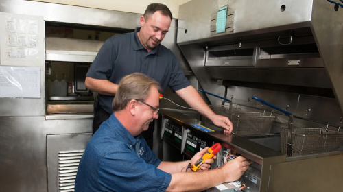 Certified technician performing commercial appliance repair services in a restaurant kitchen in Pennsville Township, NJ, fixing an appliance.